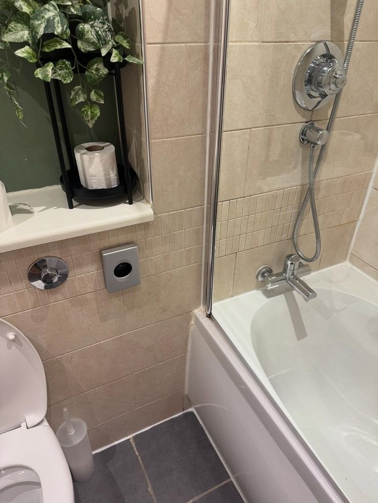 Clean bathroom with tiled walls, tub and shower