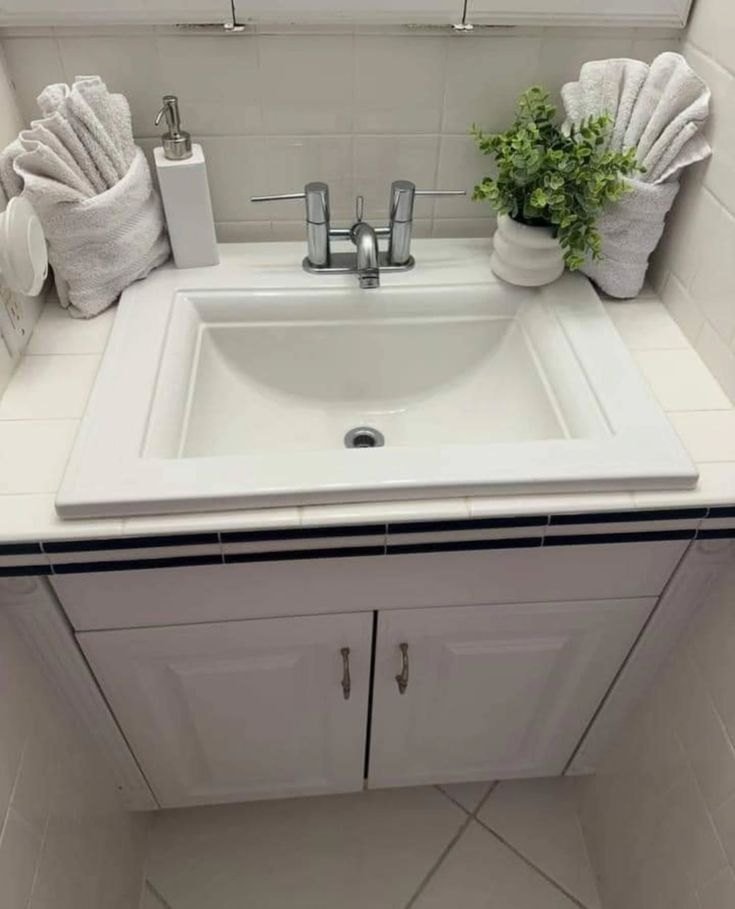 Clean bathroom sink with folded towels and a plant