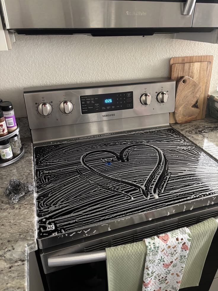 Stovetop covered in soap suds with a heart drawn in them during cleaning
