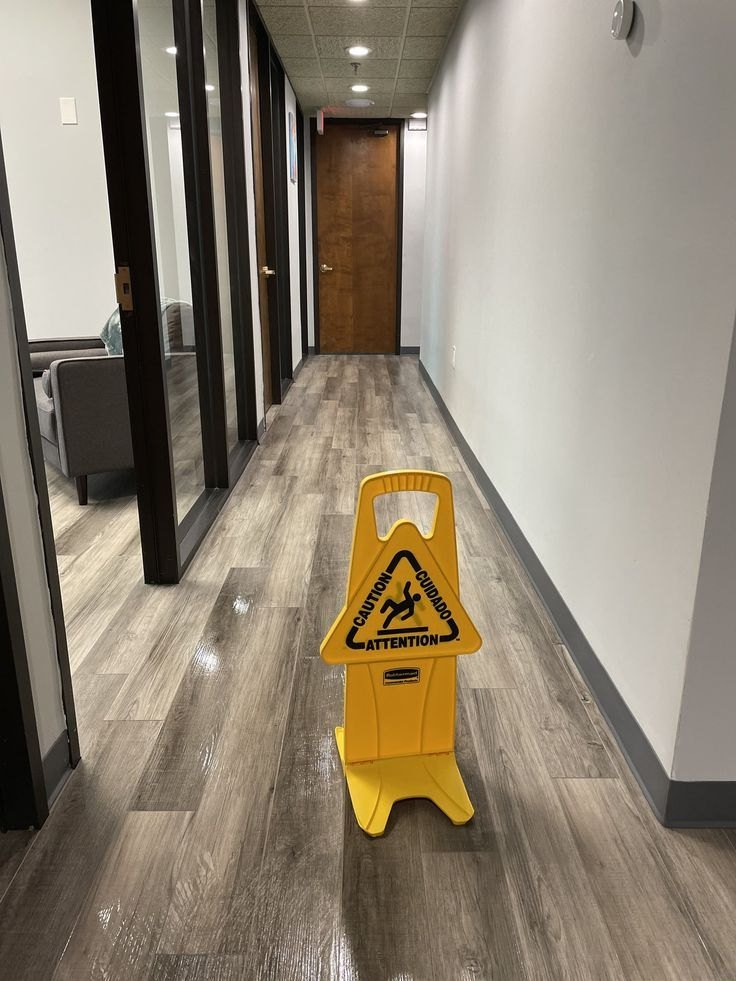 Office hallway with freshly mopped wood-look floors and a wet floor sign